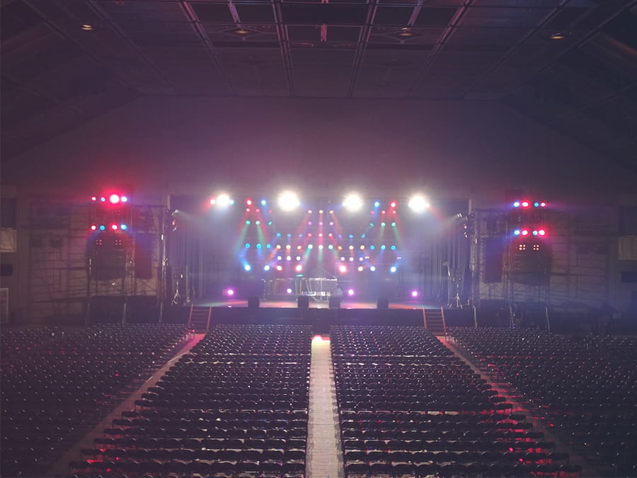 屋内大型施設のステージでイベントの為、赤や青や黄色などの照明を照らして準備している様子