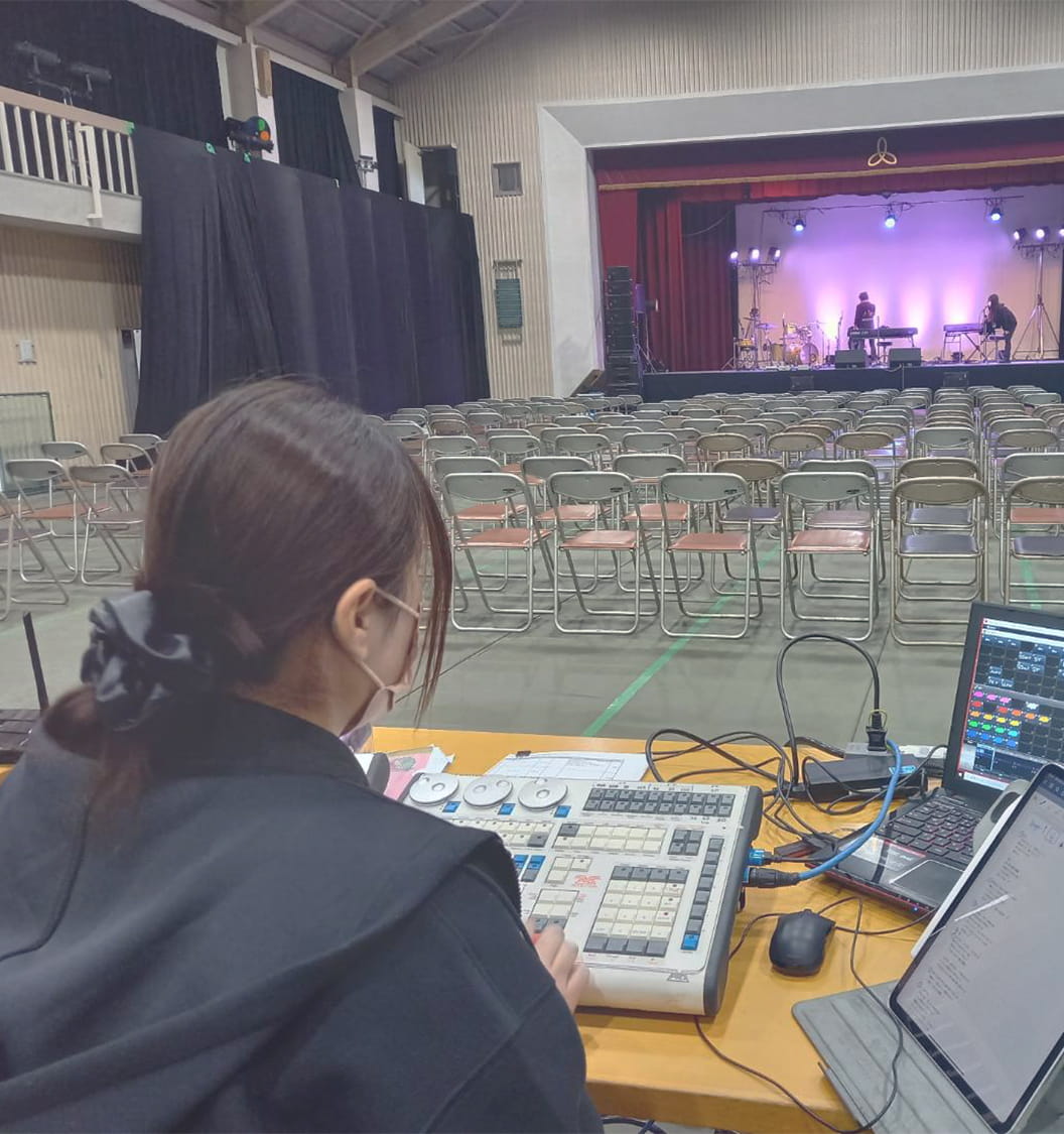 PAミキサーを使用してステージの照明や音楽を設定していく女性スタッフ